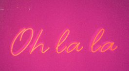 A yellow neon light sign reading 'Oh la la' on a pink background