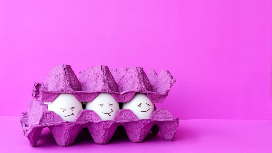 A purple egg carton with three eggs inside showing happy, angry and neutral expressions.